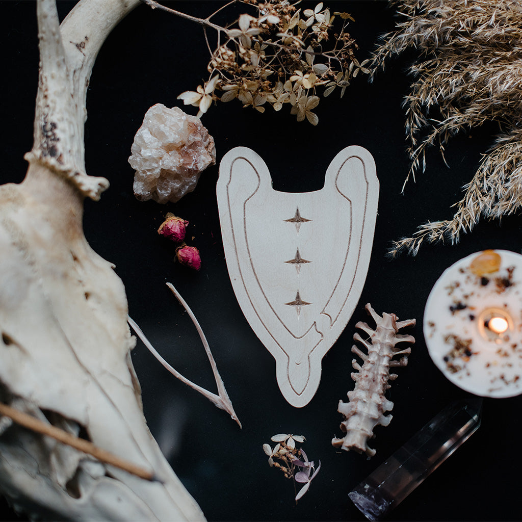 wooden wishbone art therapy project surrounded by dried flowers, crystals, and candles